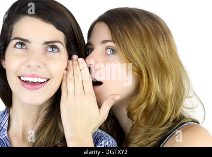 Portrait of young woman telling a secret to another woman Stock Photo