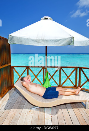 man tans on a terrace of water villa Stock Photo