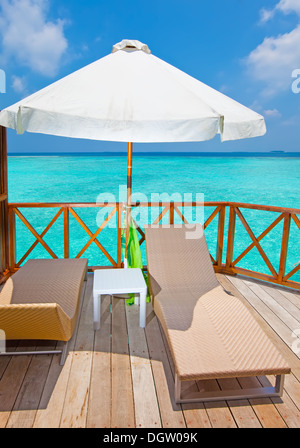 Parasol and chaise lounges on a terrace Stock Photo