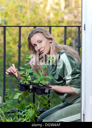 The young woman lands seedling on a balcony Stock Photo
