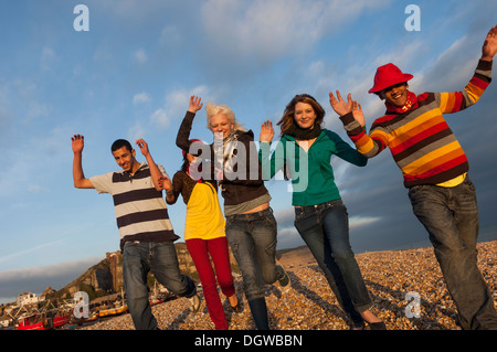 Enthusiastic teenage friends running along the beach. Hastings UK Stock Photo