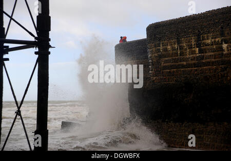 People watch the waves crashing in by Brighton Pier this morning as the worst storms named St Jude hit the UK Stock Photo