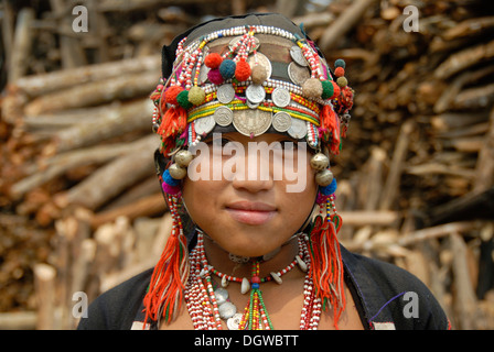 Portrait of a girl of the Akha Eupa ethnic group wearing traditional costume and headdress with colourful pompoms and silver Stock Photo