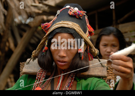 Portrait of a young woman of the Akha Eupa ethnic group concentrating on spinning cotton, wearing traditional clothes and a Stock Photo