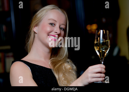 Young blond woman drinking a glass of champagne Stock Photo