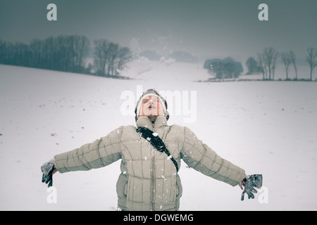 Ecstatic middle aged woman enjoying snow in winter. Stock Photo