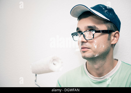 Young man decorating interior with paint roller. Stock Photo