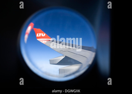 View from the cabin window to the wing of an Airbus aircraft in flight, with winglet and the logo of airline LTU Stock Photo