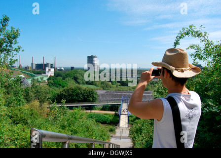Tourist visiting the Ruhr area, young man taking pictures of the industrial landscape with a digital camera, gasometer Stock Photo