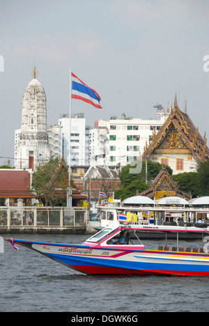 Boat on the Mae Nam Chao Phraya River, Thai national flag, in the back a Buddhist temple, Bangkok, Thailand, Southeast Asia Stock Photo