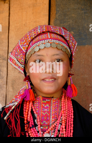 Portrait, smiling girl of the Akha Pala ethnicity, dress, traditional dress in black and pink, scarf with silver coins Stock Photo