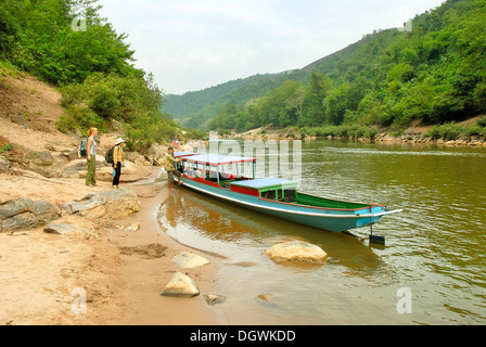 Tourists on the shore, river valley, wooden boat on the Nam Ou river in Muang Khoua, Phongsali province, Laos, Southeast Asia