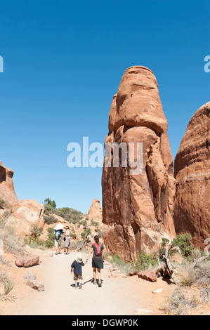 Mother and child hiking along a trail, red sandstone cliffs, rock formations at Devils Garden Trailhead in Arches National Park Stock Photo