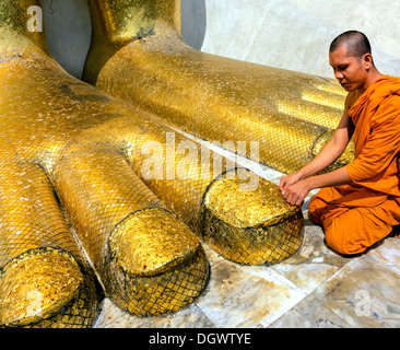 Monk praying at the feet of the golden Buddha statue of Wat Intharawihan, Wat Indra, Bangkok, Central Thailand, Thailand Stock Photo