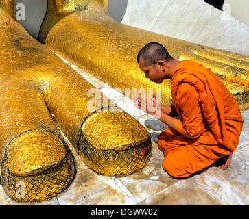 Monk praying at the feet of the golden Buddha statue of Wat Intharawihan, Wat Indra, Bangkok, Central Thailand, Thailand Stock Photo