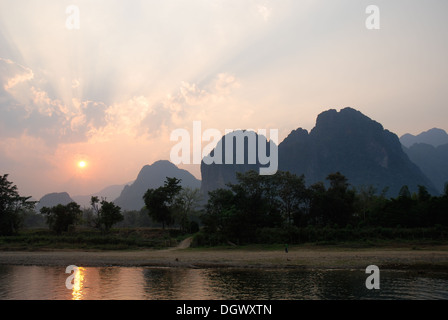 A stunning sunset over Nam song river in Vang Vieng, Laos. This atmospheric shot has  a reflection of the sun in the river Stock Photo