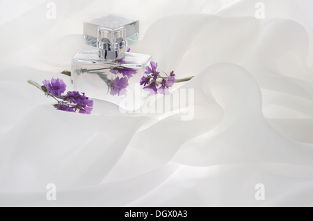 perfume bottles and flowers, empty, alone, is buried in the folds of the air, clouds of white cloth Stock Photo