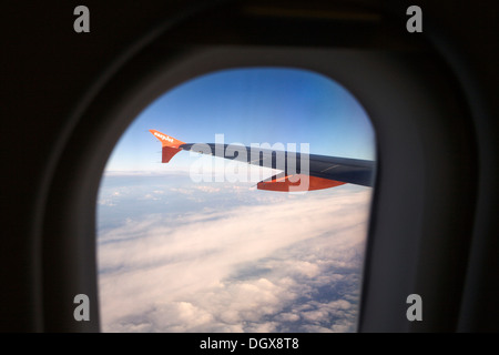View through the cabin window to the left wing of an Airbus A319-100 of the easyJet airline, in flight Stock Photo