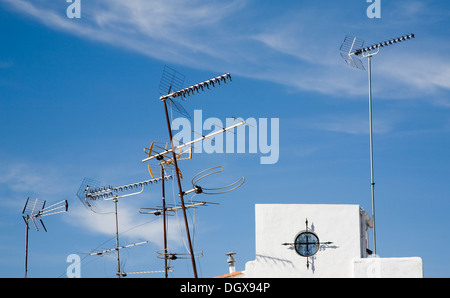 Variety of television aerials on rooftops against blue sky Spain Stock Photo
