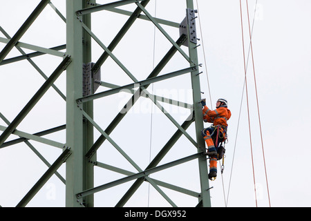 Lineman working with a wire rope hoist on a 380-kV long-distance line owned by the 50Hertz transmission system operator, track Stock Photo