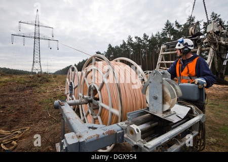 Lineman working with a wire rope hoist on a 380-kV long-distance line owned by the 50Hertz transmission system operator, track Stock Photo