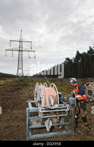 Lineman working with a wire rope hoist on a 380-kV long-distance line owned by the 50Hertz transmission system operator, track Stock Photo