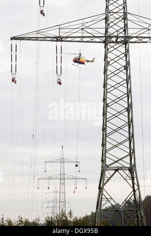 Lineman working with a wire rope hoist on a 380-kV long-distance line owned by the 50Hertz transmission system operator, track Stock Photo