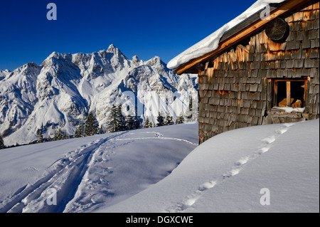 Snowbound Vordere Uentschenalpe hut with a ski track and the peak of Mt Toblermannskopf, Baad, Kleinwalsertal, Vorarlberg Stock Photo