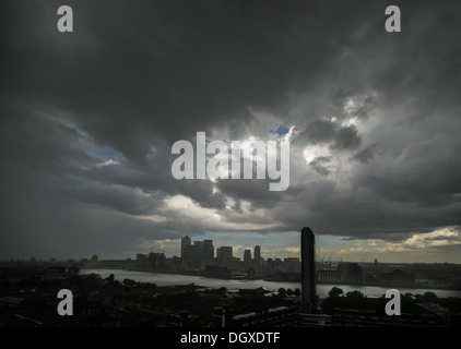 Dark storm clouds loom over the River Thames and Canary Wharf buildings in London.