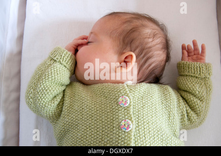 Little baby girl asleep in her crib and sucking her thumb Stock Photo