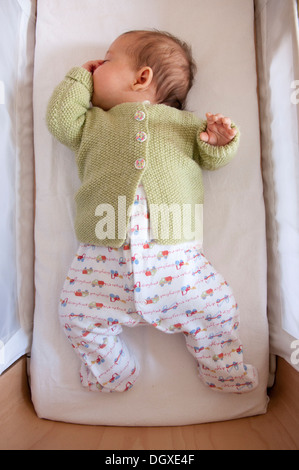 Little baby girl asleep in her crib and sucking her thumb Stock Photo