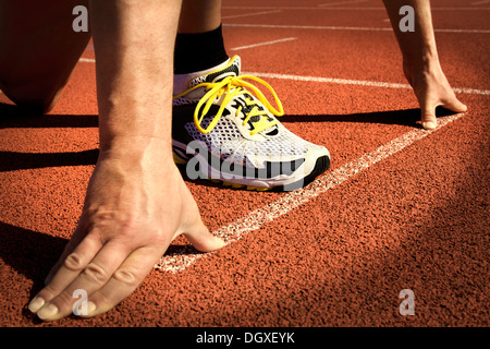Runner in a stadium is in start position with hands on the line Stock Photo