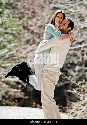 Young man picking up a young woman, both smiling, Austria Stock Photo