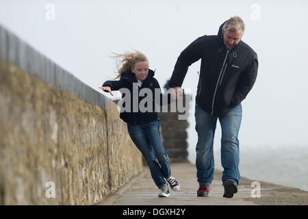 Porthcawl, Wales, UK. October 27. Strong winds at Porthcawl, South Wales as a major atlantic storm moves across the UK. The stormy weather will continue into Monday with winds gusting at up to 80mph.  Pictured are Matthew and Mia Jones of Porthcawl.  Matthew Horwood / Alamy Live News Stock Photo