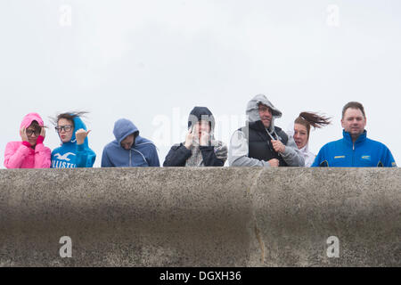 Porthcawl, Wales, UK. October 27. Strong winds at Porthcawl, South Wales as a major atlantic storm moves across the UK. The stormy weather will continue into Monday with winds gusting at up to 80mph.  People look out at the sea from a sea wall.  Matthew Horwood / Alamy Live News Stock Photo