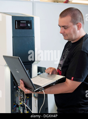 Engineer is uploading new firmware into the system of the Siemens Charge CP700A charging station in a development laboratory Stock Photo