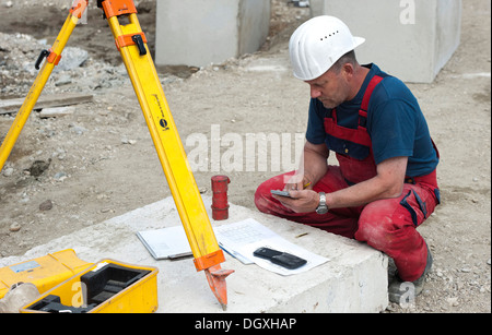 A structural engineer is taking measurements of a possible soil dropping during a building site load test, at a construction Stock Photo