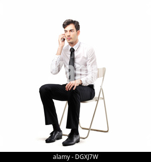 Young office worker sitting on a chair calling someone with a mobile phone Stock Photo