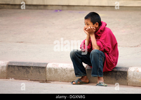 Street child sadly gazing into the distance with his head resting on his hands, Pokhara, Nepal, Asia Stock Photo