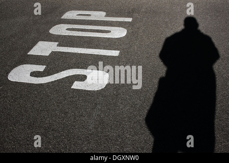 Road markings, ground markings, stop notice on asphalt, shadow of a person Stock Photo