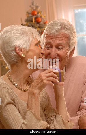 Mature couple exchanging presents in front of a Christmas tree Stock Photo