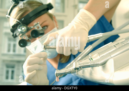 Dentist wearing magnifying loupes preparing a drill Stock Photo