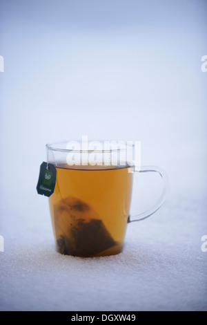 Tea cup with herbal tea standing in the snow Stock Photo