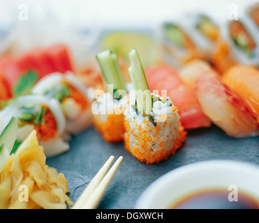 Assorted sushi rolls with pickled ginger and chopsticks on a slate surface Stock Photo