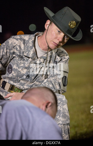 A female Drill Sergeant instructor monitors a Drill Sergeant candidate at the US Army Drill Instructors School Fort Jackson during the entry physical training test early morning September 27, 2013 in Columbia, SC. While 14 percent of the Army is women soldiers there is a shortage of female Drill Sergeants. Stock Photo