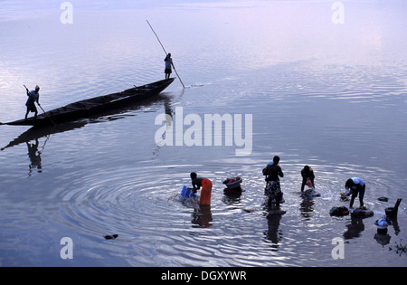 Women washing in River Nicer with two men rowing in a traditional boat. Stock Photo