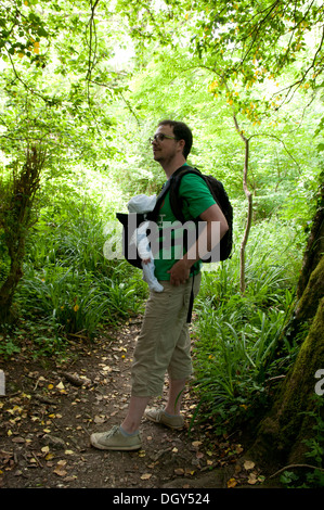 Father carrying his little baby in a sling enjoying a walk in the countryside Stock Photo