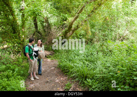 New parents with their little baby in a sling enjoying a walk in the countryside Stock Photo