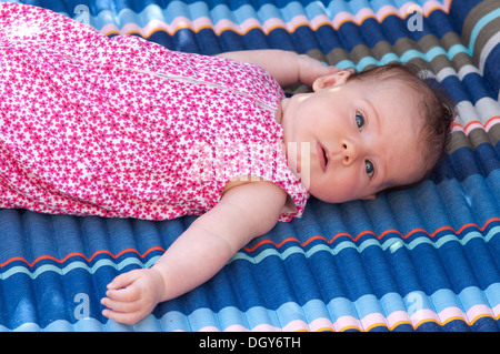Little baby girl lying down looking at the camera worried Stock Photo