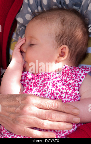 Close-up of a little baby girl being held sleeping and sucking her thumb Stock Photo
